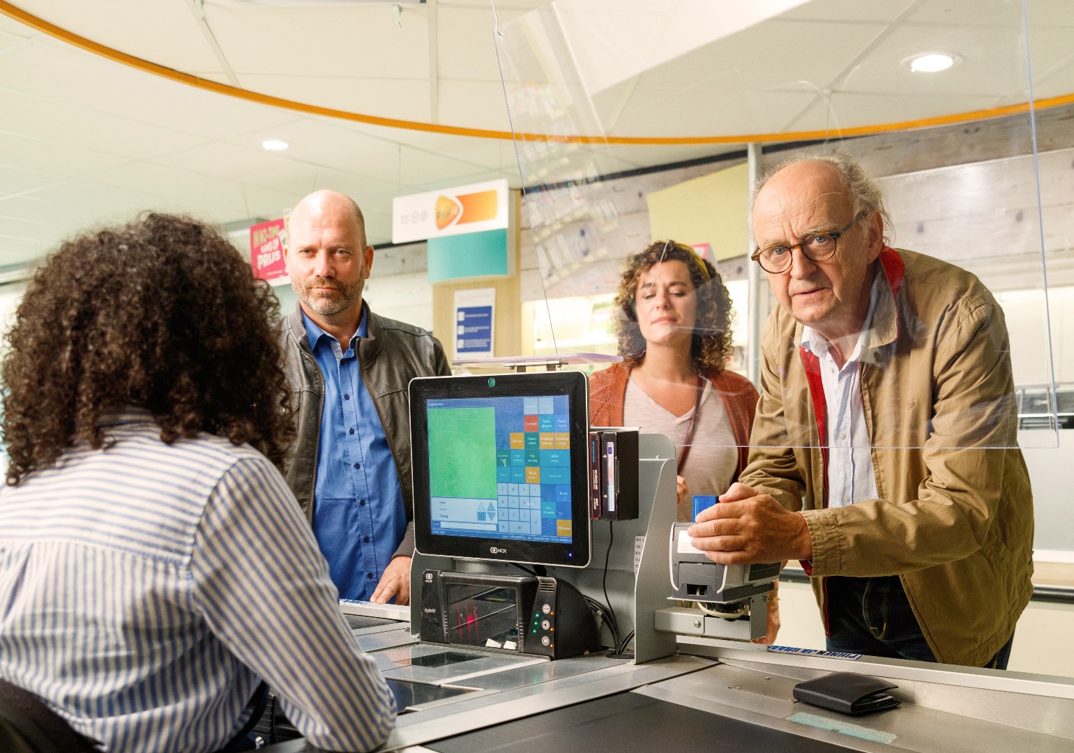 Een klant schermt  bij de kassa de pinautomaat af bij het intoetsen van zijn pincode