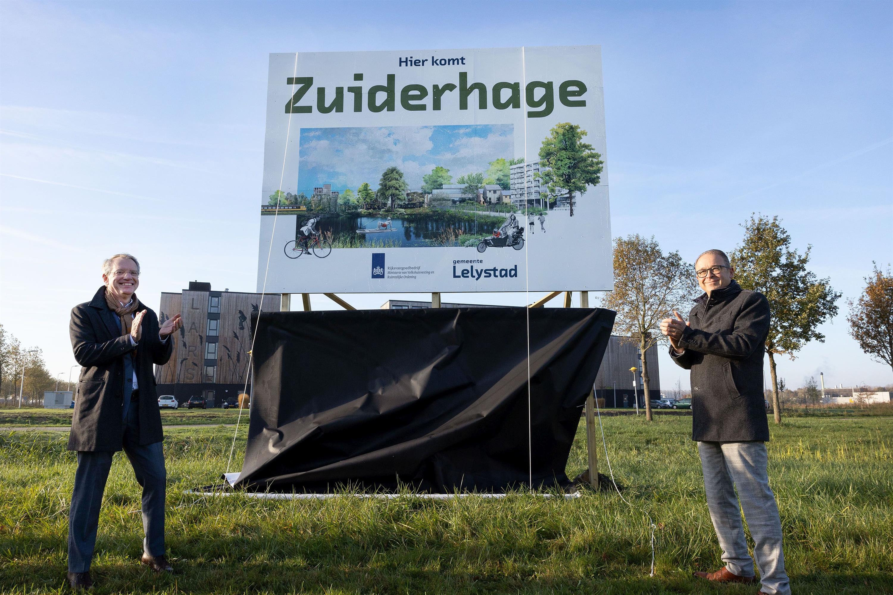 Martijn van Berkel van het Rijksvastgoedbedrijf (links op de foto) en wethouder Dennis Grimbergen onthullen de naam van het nieuwe stadsdeel: Zuiderhage. Foto: Fotostudio Wierd