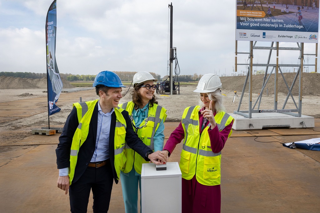 Minister Mona Keijzer, burgemeester Mieke Baltus en Bram van Rijt van VDL De Meeuw geven het startsein voor de bouw van de tijdelijke school met kinderopvang in Zuiderhage