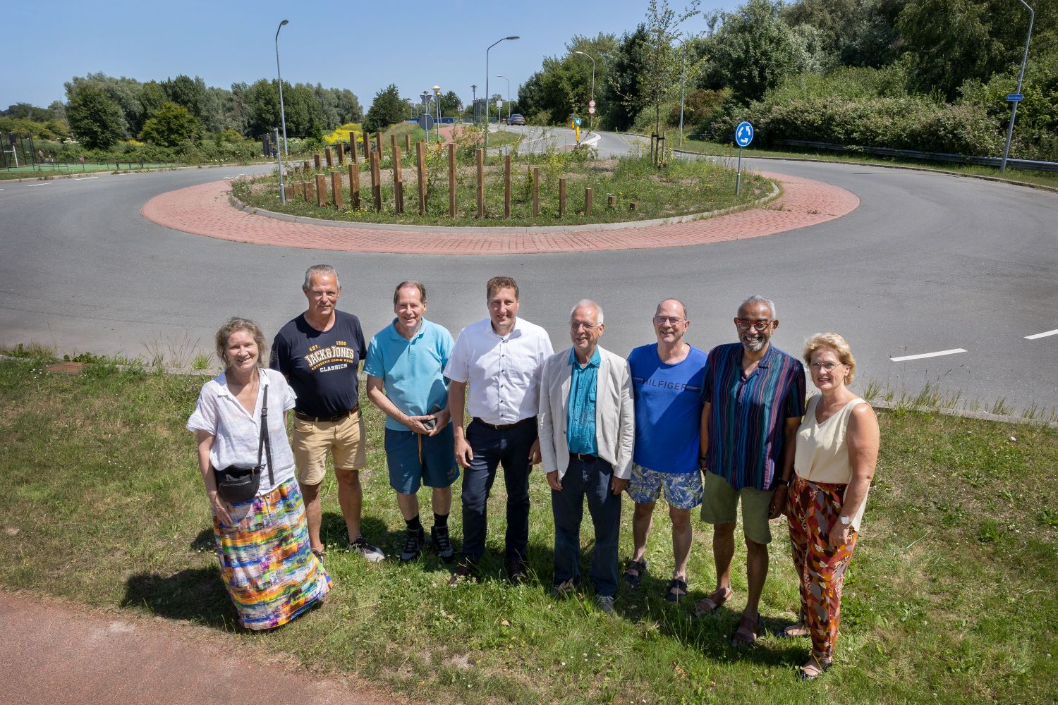 Samen met bewoners poseren gedeputeerde Harold Hofstra en wethouder Sjaak Kruis voor de nieuwe rotonde bij de Hollandse Hout