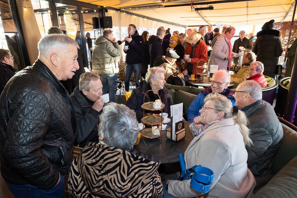 Bezoekers van de nieuwjaarsontmoeting zijn met elkaar in gesprek op het terras van Mr Lely