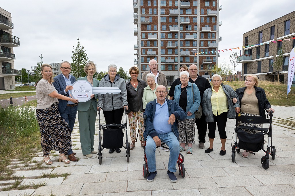 Wethouder Dennis Grimbergen, directeur bestuurder Martine Visser van Centrada en directeur bestuurder Marieke Voogt van Welzijn Lelystad overhandigen symbolisch een grote sleutel aan bewoners van Hooghe Bomen