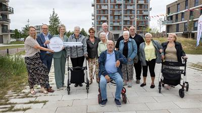 Wethouder Dennis Grimbergen, directeur bestuurder Martine Visser van Centrada en directeur bestuurder Marieke Voogt van Welzijn Lelystad overhandigen symbolisch een grote sleutel aan bewoners van Hooghe Bomen