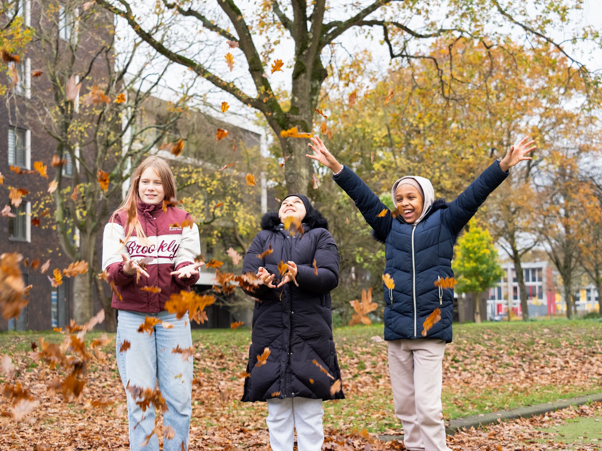 Kinderen gooien bladeren omhoog en hebben plezier in de Zuiderzeewijk