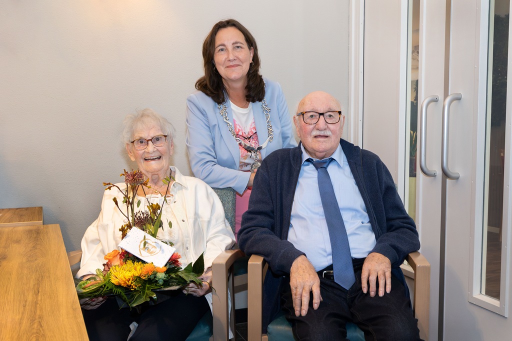 Burgemeester Mieke Baltus achter het jubilerende echtpaar Trudy en Ted Warren