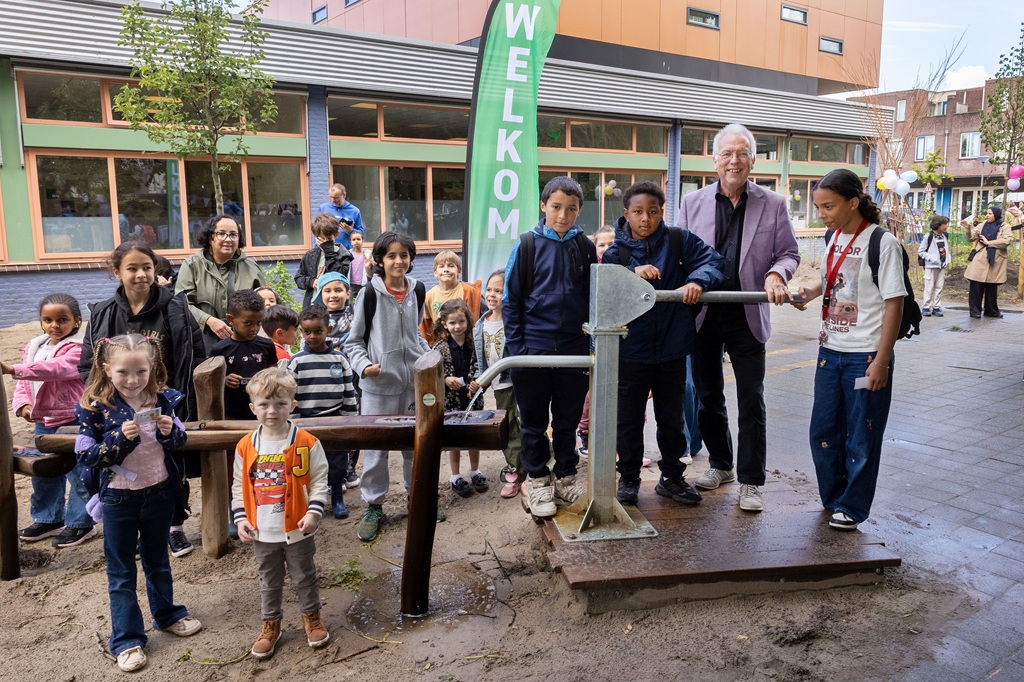 Trotse leerlingen van Driestromenland laten wethouder Sjaak Kruis hun vernieuwde groene schoolplein zien