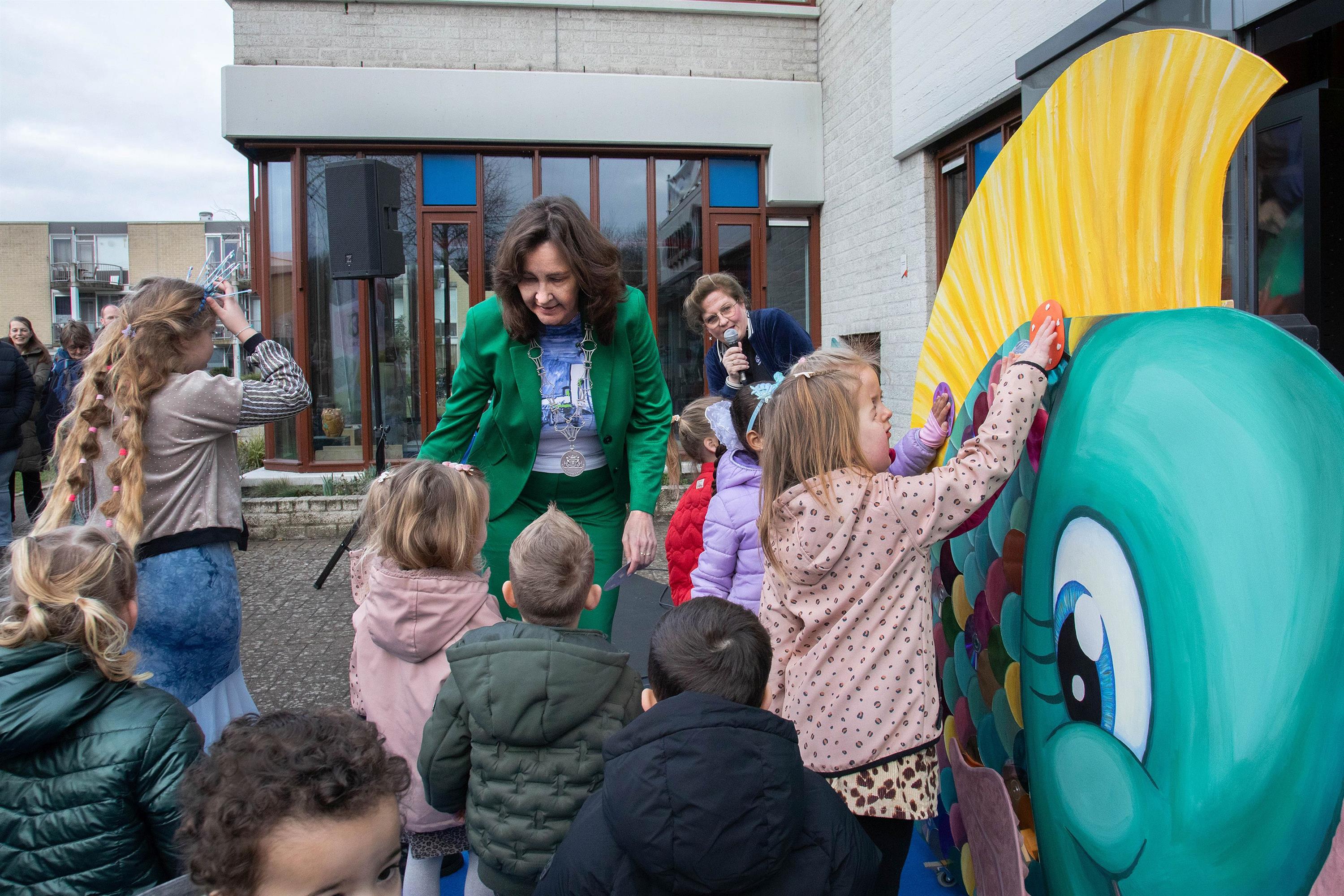 Burgemeester Mieke Baltus opent samen met peuters en kleuters het Peuter Kleuter Festijn in De Kubus door een glitterschub te plakken op de ‘mooiste vis van de zee’.