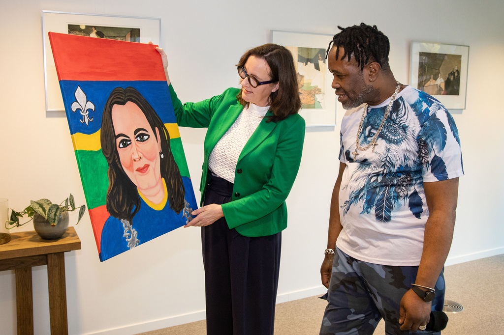 Burgemeester Mieke Baltus en kunstenaar Regilio Josua bekijken het portret in pop-artstijl dat Regilio van de burgemeester heeft gemaakt