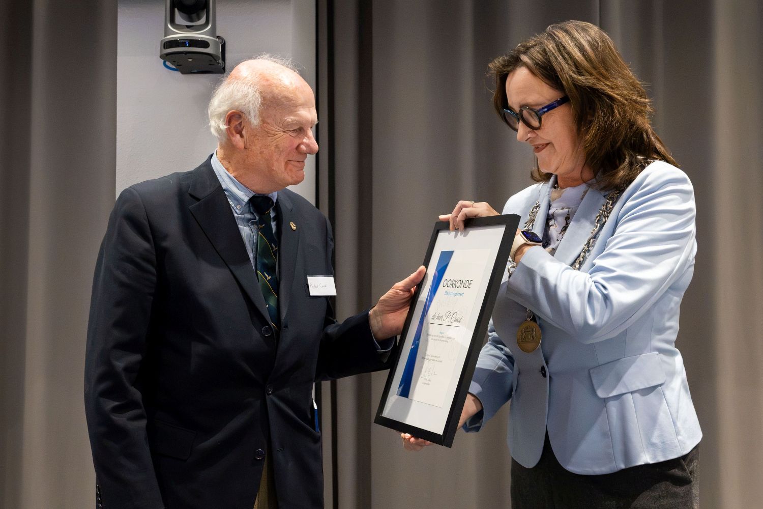 Burgemeester Mieke Baltus overhandigt het Stadscompliment aan Pieter Cassé als  waardering voor zijn jarenlange inzet voor de Buurtbusvereniging Lelystad.