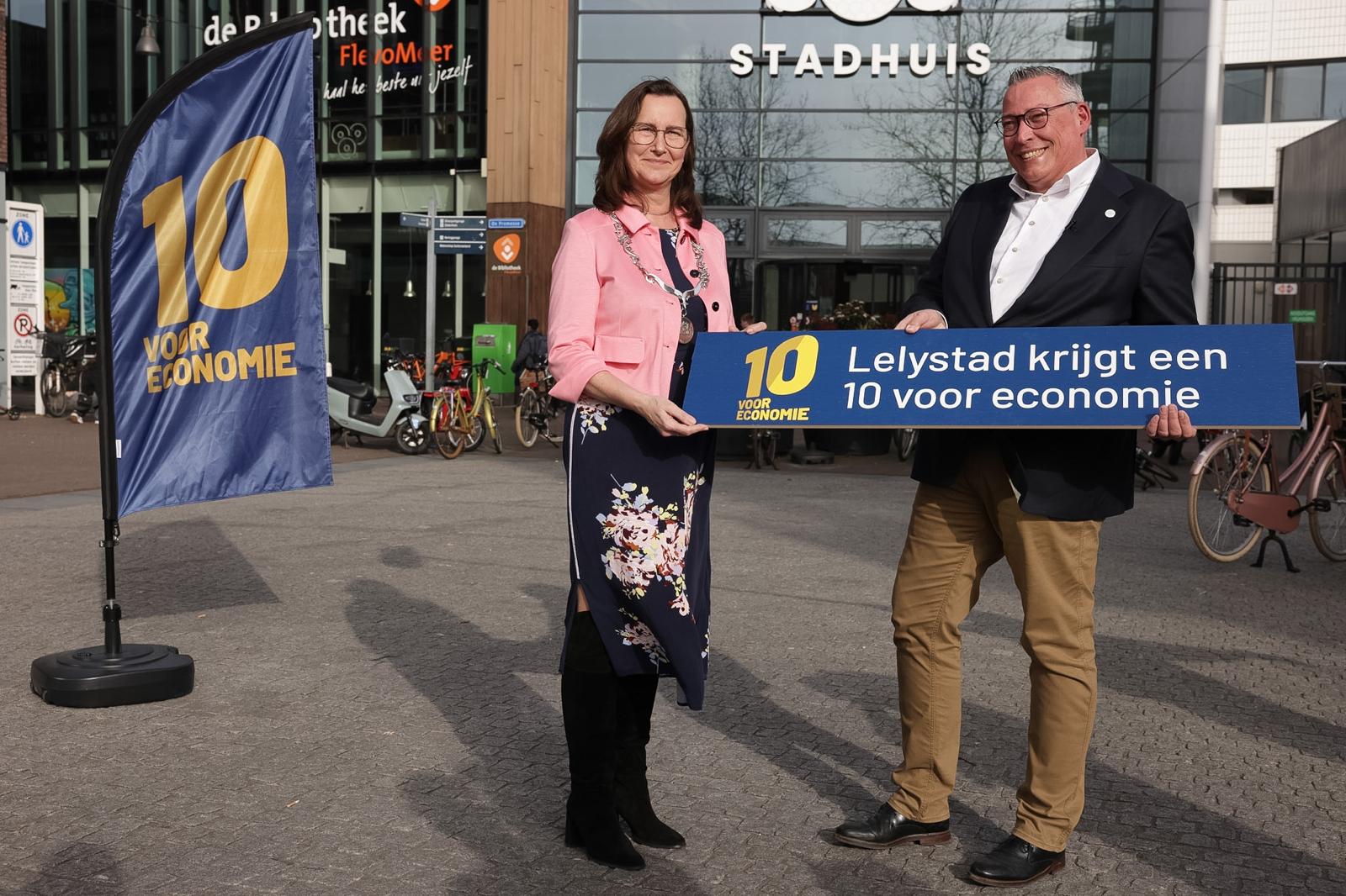 Burgemeester Mieke Baltus neemt het bord 'Lelystad krijgt een 10 voor economie' in ontvangst