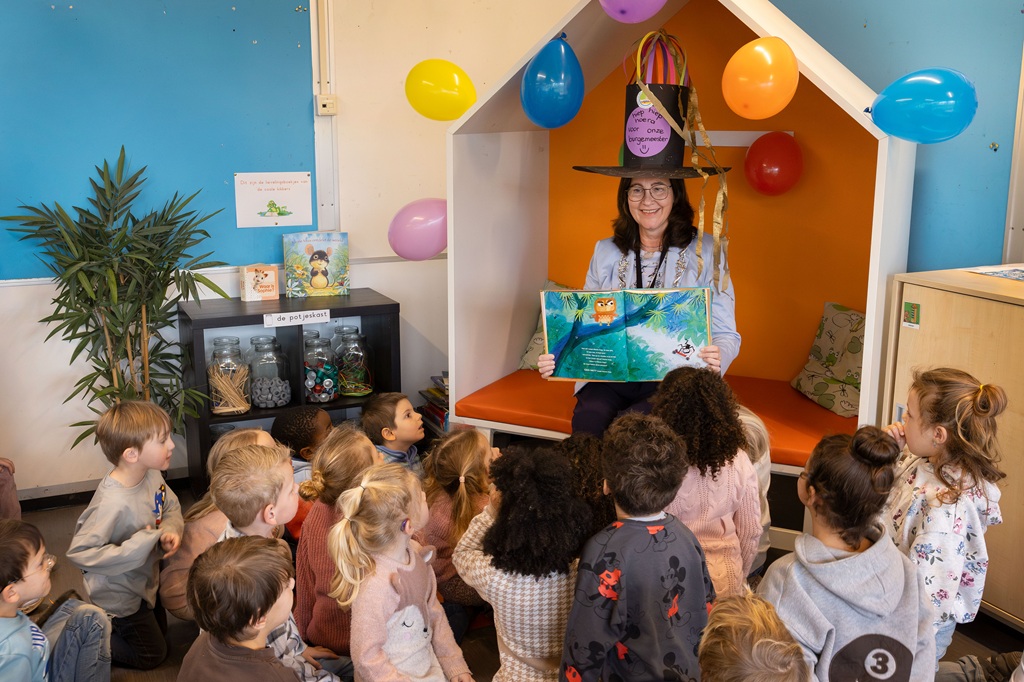 Met een heuse verjaardagshoed op leest burgemeester Mieke Baltus voor aan peuters en kleuters