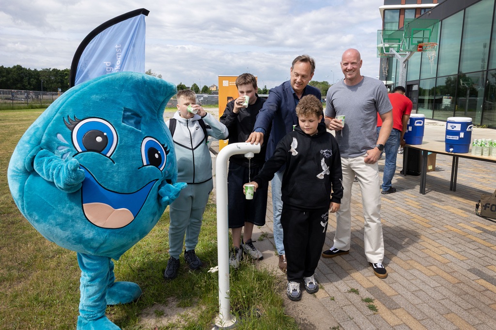 Wethouder Jan-Nico Appelman tapt samen met Porteum-leerlingen water bij een tappunt op het schoolplein
